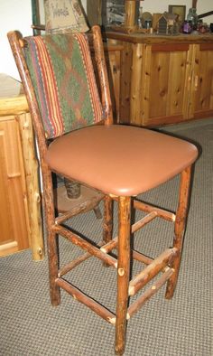 a wooden bar stool with a leather seat and back rest in a kitchen next to a counter