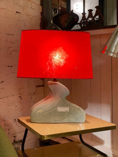 a red lamp sitting on top of a wooden table