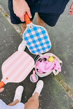 two people holding carrots in their hands while standing next to some other items on the ground