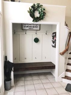 an entryway with a bench and wreath on the wall