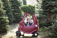 a small child in a red car with a christmas tree on top