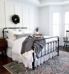 a bedroom with white walls and black iron bedspread, rugs, and furniture