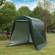 a tent is set up in the middle of a field with trees and grass around it