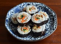 sushi is served in a blue and white bowl on a wooden table with chopsticks