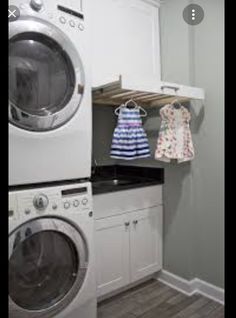 a washer and dryer in a small laundry room with white cabinets, wood flooring and gray walls