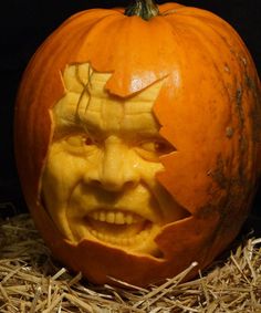 an orange pumpkin with a face carved into it's side, sitting on hay