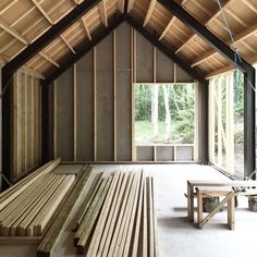 the inside of an unfinished building with wooden benches and tables in front of windows that are framed by wood planks