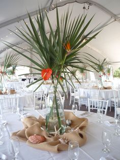 a vase filled with water and flowers on top of a table covered in white linens