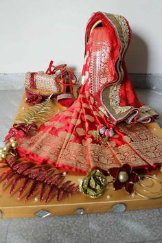 a red and gold saree sitting on top of a piece of wood next to other items