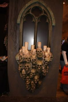 a group of candles that are sitting in front of a wall with skulls on it