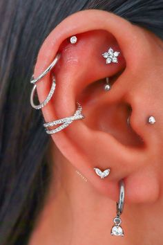 a woman with three different ear piercings on her left side and one behind the ear