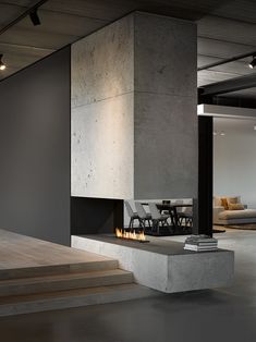 a modern fireplace in the middle of a room with stairs leading up to an open floor plan