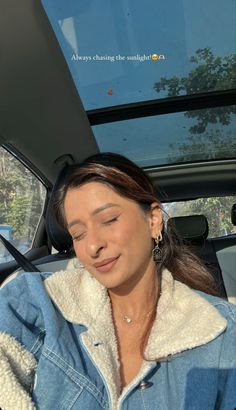 a woman sitting in the back seat of a car with her eyes closed and looking down