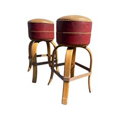 two wooden stools with red leather seats on each side and wood feet, against a white background