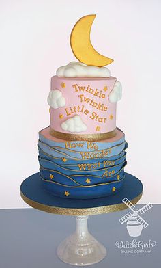 a three tiered cake with a moon and stars on top, sitting on a plate