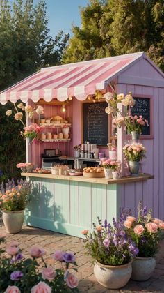 a pink and white striped awning next to potted flowers in front of a small bar