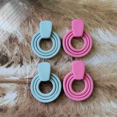 three pairs of pink and blue earrings on a fur rug with an animal print background