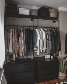 an organized closet with clothes hanging on rails