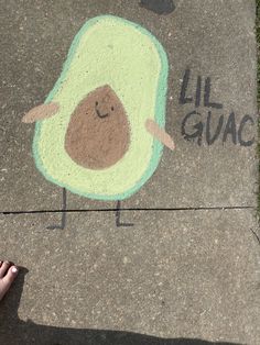 someone is standing on the sidewalk with their hand in front of a painted avocado