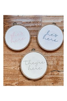 three embroidered hoops with words on them sitting on a wooden floor next to each other