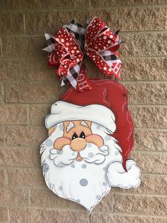 a santa clause door hanger on the side of a brick wall with red and white polka dots