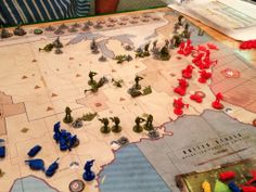 a board game with red and blue plastic figures on the map in front of it