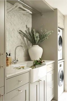 a white vase filled with flowers sitting on top of a kitchen counter next to washer and dryer