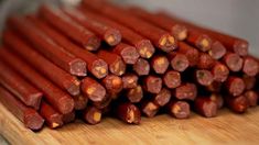 a pile of sausage sticks sitting on top of a wooden cutting board