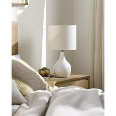 a white lamp sitting on top of a table next to a bed