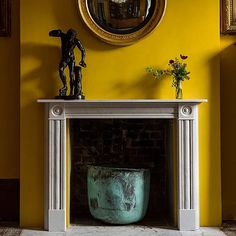 a fireplace with yellow walls and a mirror above it