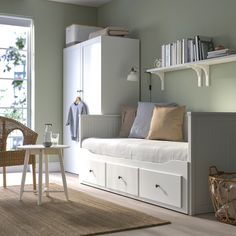 a white daybed sitting in a bedroom next to a window with bookshelves