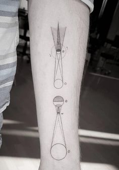 a person with a tattoo on their leg that has an image of a clock and a telescope