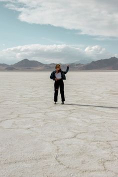 a woman standing in the middle of an empty desert