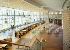 people are sitting at tables in the middle of a large room with lots of windows