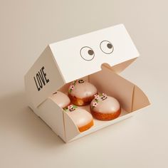 an open box filled with donuts sitting on top of a white table next to each other