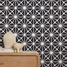 a white vase sitting on top of a wooden table next to a black and white wall