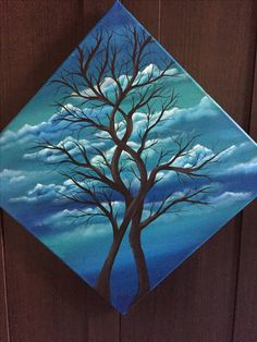 a painting of a tree on a blue and white diamond with clouds in the background