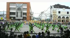 a group of people that are standing in the middle of a street with green outfits