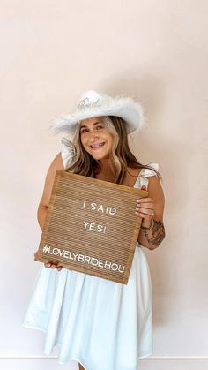 a woman in a white dress holding up a sign