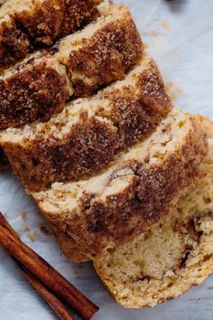 slices of cinnamon swirl bread sitting on top of a piece of parchment paper next to cinnamon sticks