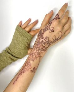 two hands holding each other with tattoos on their arm and wrist, both showing different designs