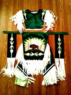 a green and white uniform with fringes on top of a wooden floor in front of a wood floor