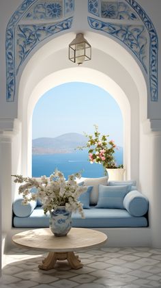 a blue and white couch sitting under a window next to a vase with flowers on it