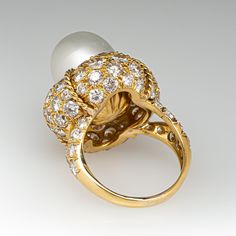 This magnificent cocktail ring is centered with one (1), post set, cultured South Sea pearl. The pearl tops a domed setting is bead set sixty-four (64), bead set, round brilliant cut diamonds. The ring has a split shank design and is accented with seven (7), bead set, round brilliant cut diamonds on each side. The ring measures 21.7mm at the top, rises 18.6mm above the finger, tapering to 2.4mm wide and 1.1mm thick at the base of the shank. The ring is currently size 7. Classic Diamond Ring With Cabochon Cut, Classic Diamond Cabochon Ring, Elegant White Gold Diamond Ring With Cabochon, Formal Round Cabochon Diamond Ring, Formal Cabochon Diamond Ring, Elegant White Domed Jewelry, Classic Cabochon Diamond Ring For Anniversary, White Diamond Dome Ring For Formal Occasions, White Pearl Ring With 17 Jewels For Formal Occasions