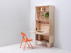 an orange chair sitting in front of a desk with a wooden bookcase on it