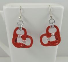 red and white heart shaped earrings with silver accents on a white cup stand, ready to be worn