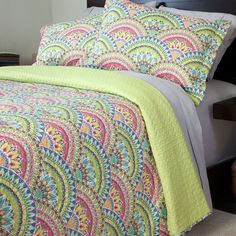 a bed with a colorful bedspread and pillows