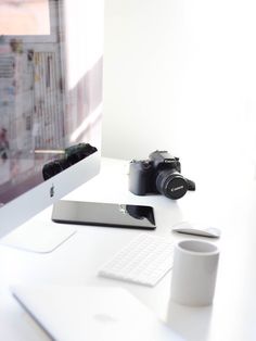 a white desk topped with a computer monitor next to a keyboard