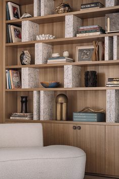 a white chair sitting in front of a wooden book shelf