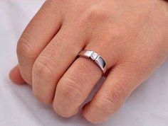 a person's hand with a silver ring on top of their finger and the word love written in it